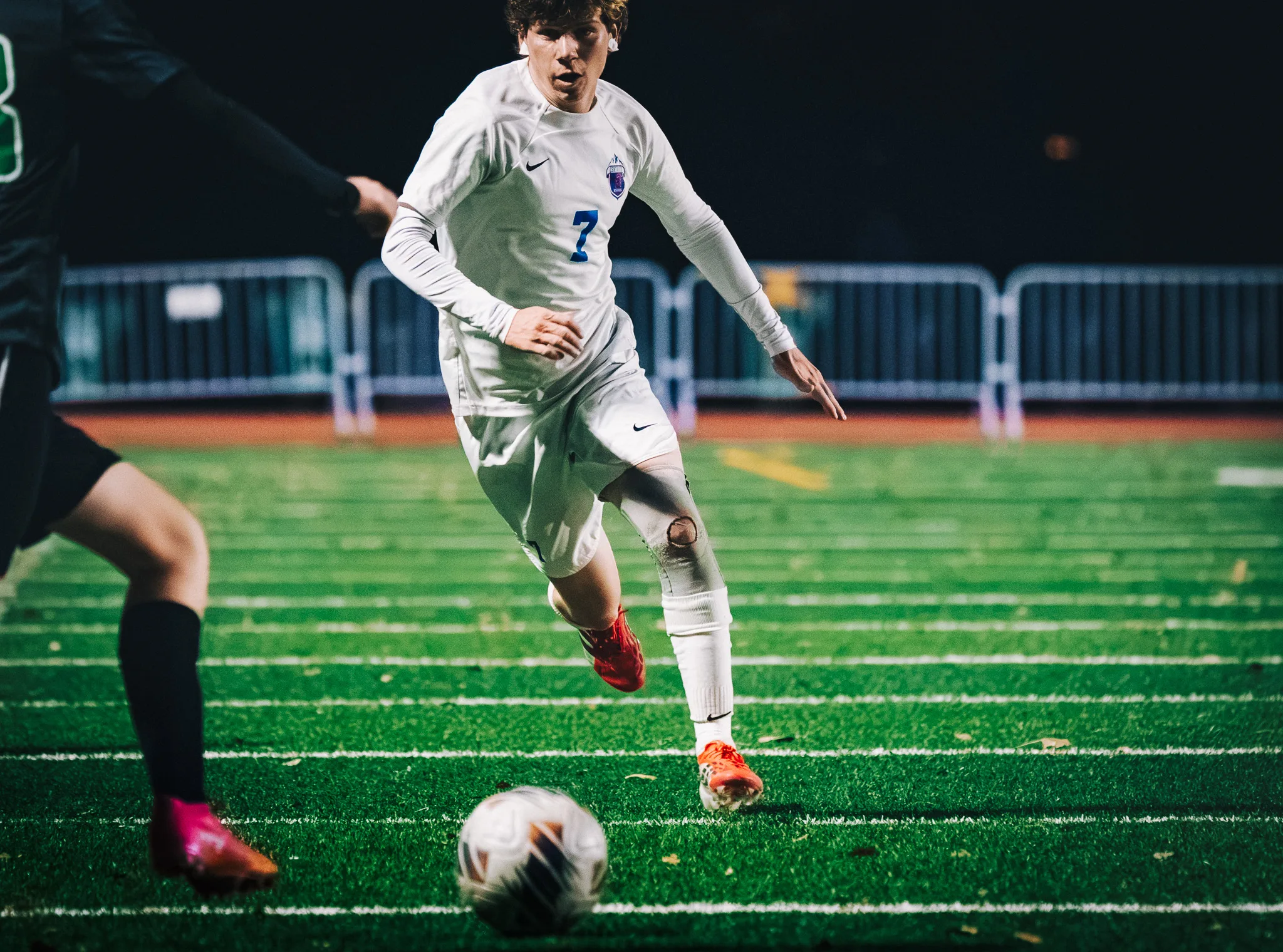 Centaurus number 7 runs at the ball with his eyes on it, a Niwot player reaching in at the left edge