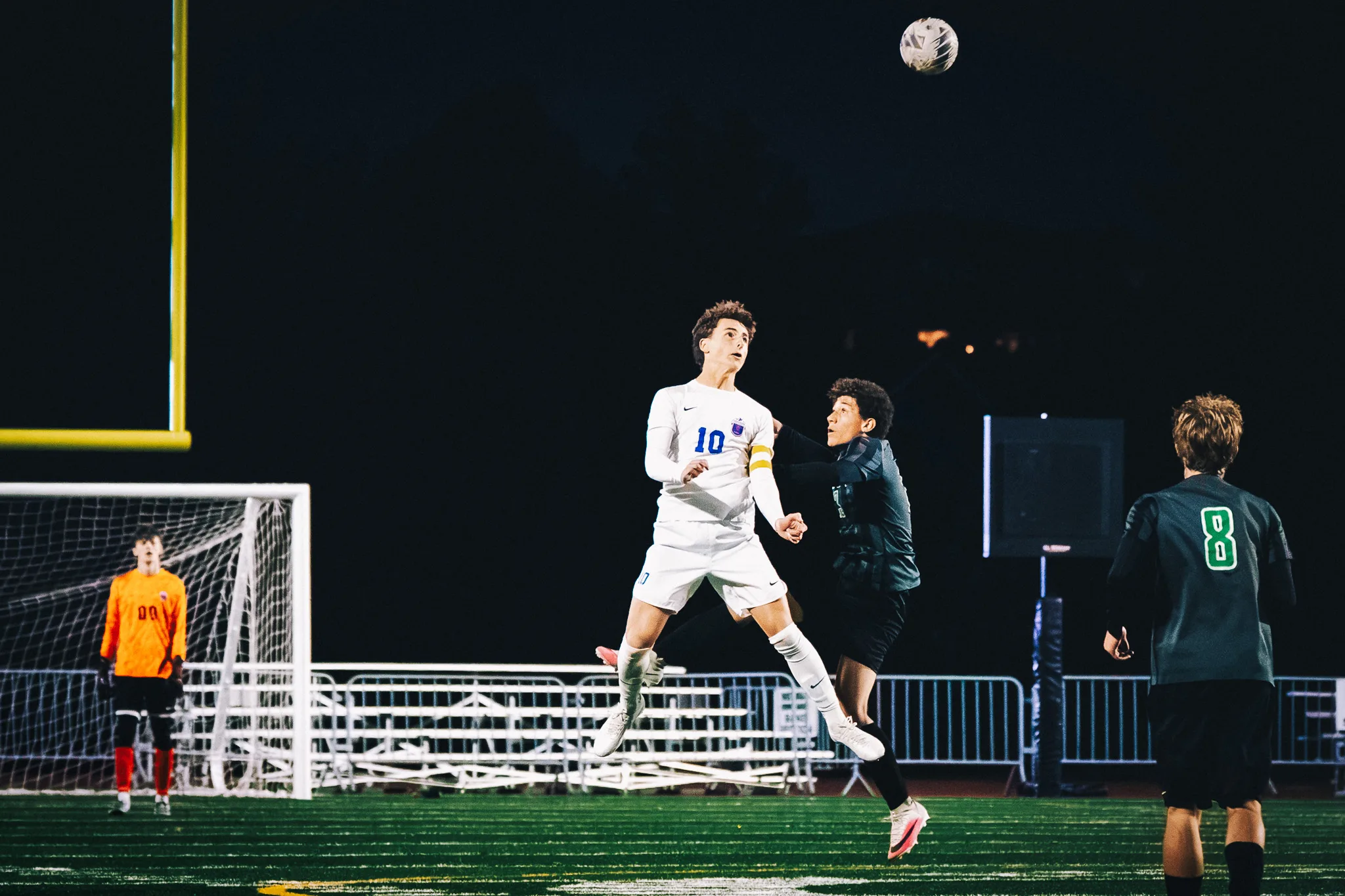 Centaurus number 10 in a captain's armband rises for a high ball against a Niwot player as Niwot number 8 watches and the Centaurus goalkeeper in orange, number 00, waits in the goal