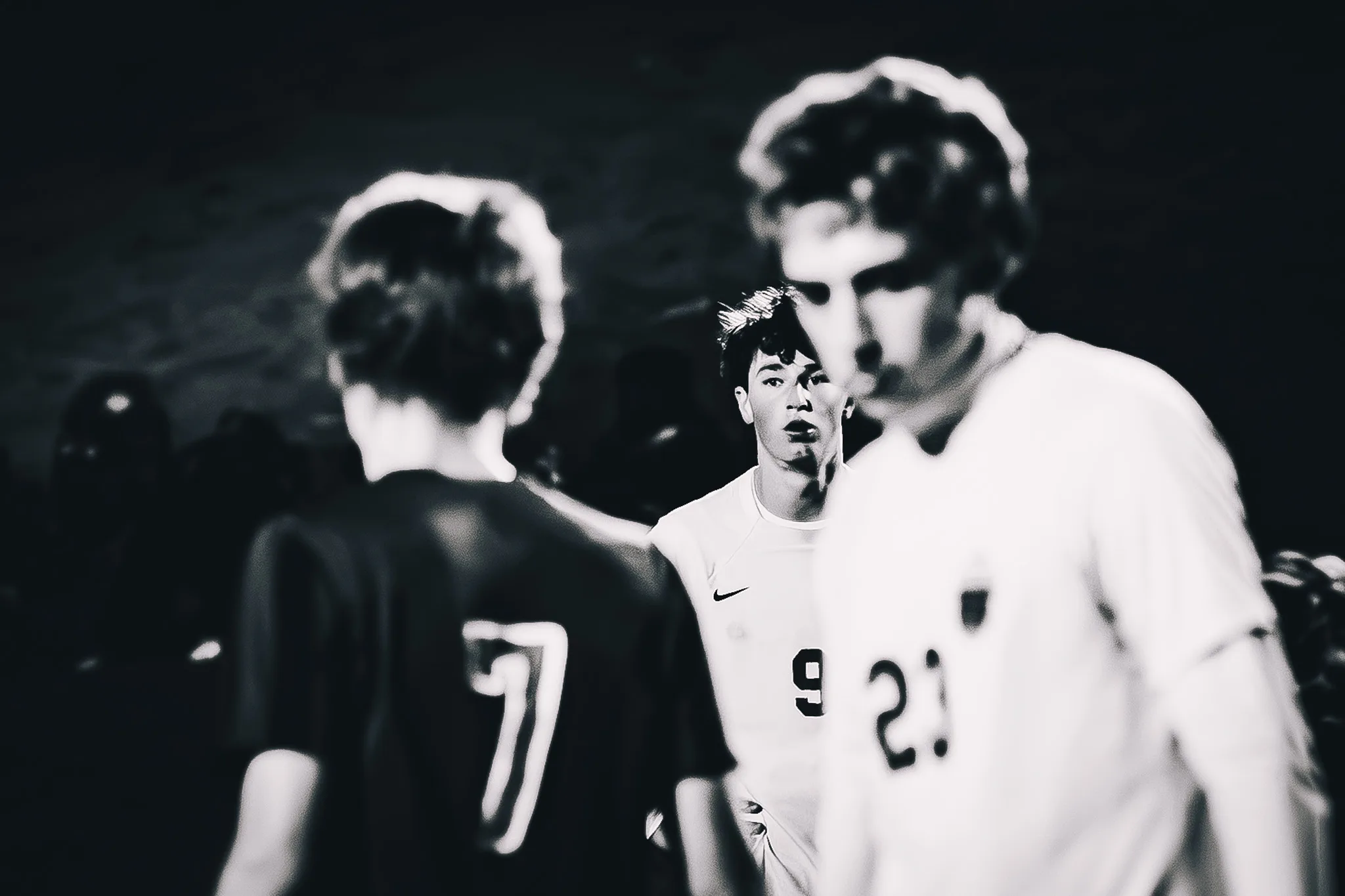 In black and white, Centaurus number 9 looks ahead between Niwot number 7 and a blurred Centaurus teammate in the foreground
