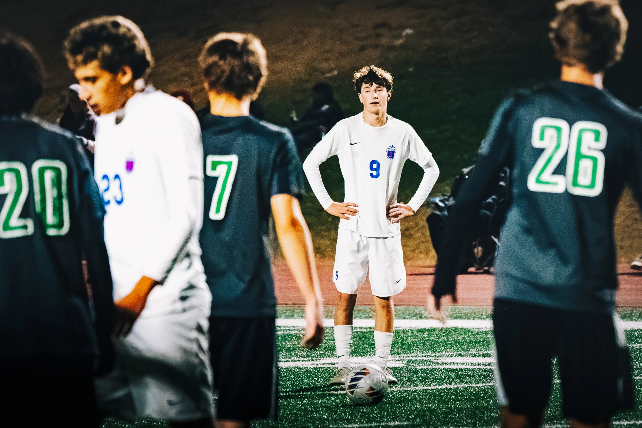 Hands on his hips, Centaurus number 9 stands over the ball as Niwot numbers 20, 7 and 26 and Centaurus number 23 walk past in the foreground