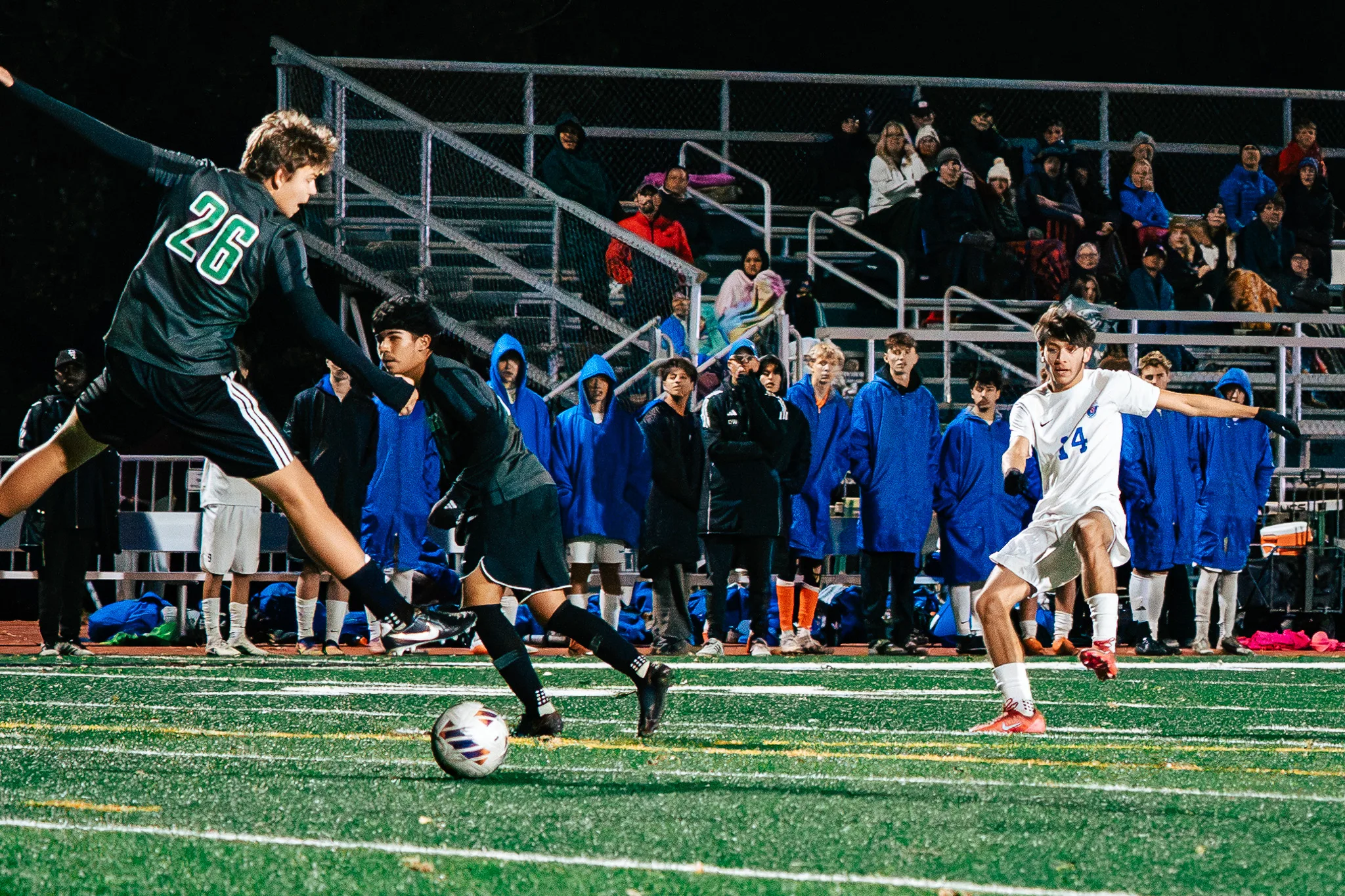 Niwot number 26 follows through on a clearance as Centaurus number 14 closes in with his arms out, fans in the bleachers watching