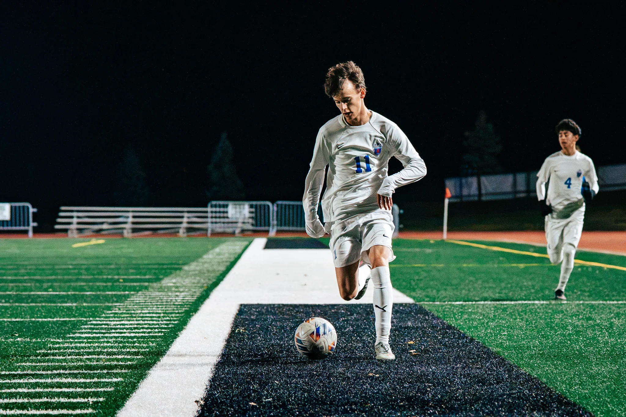 Centaurus number 11 dribbles along the sideline with his eyes on the ball as Centaurus number 4 jogs up behind him