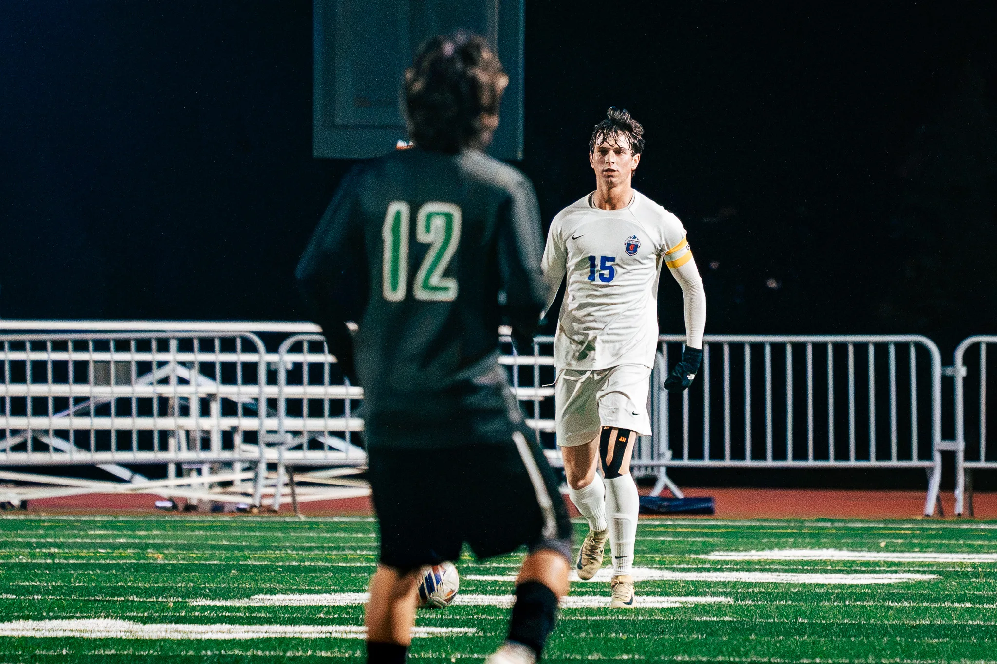 Centaurus number 15, in a yellow armband, steps toward Niwot number 12, who has the ball with his back to the camera