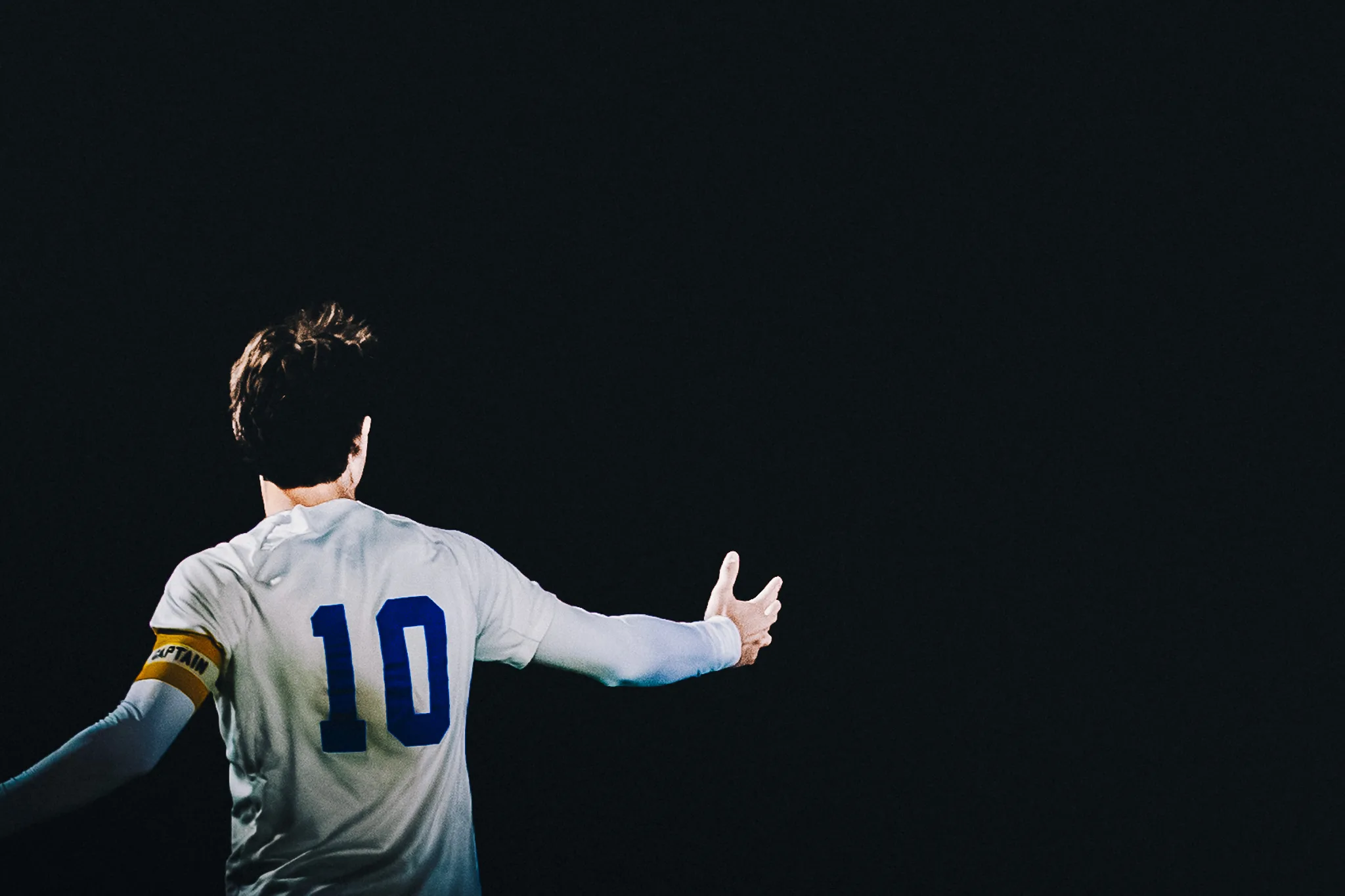 Seen from behind against the dark, Centaurus number 10 in a captain's armband spreads his arms wide