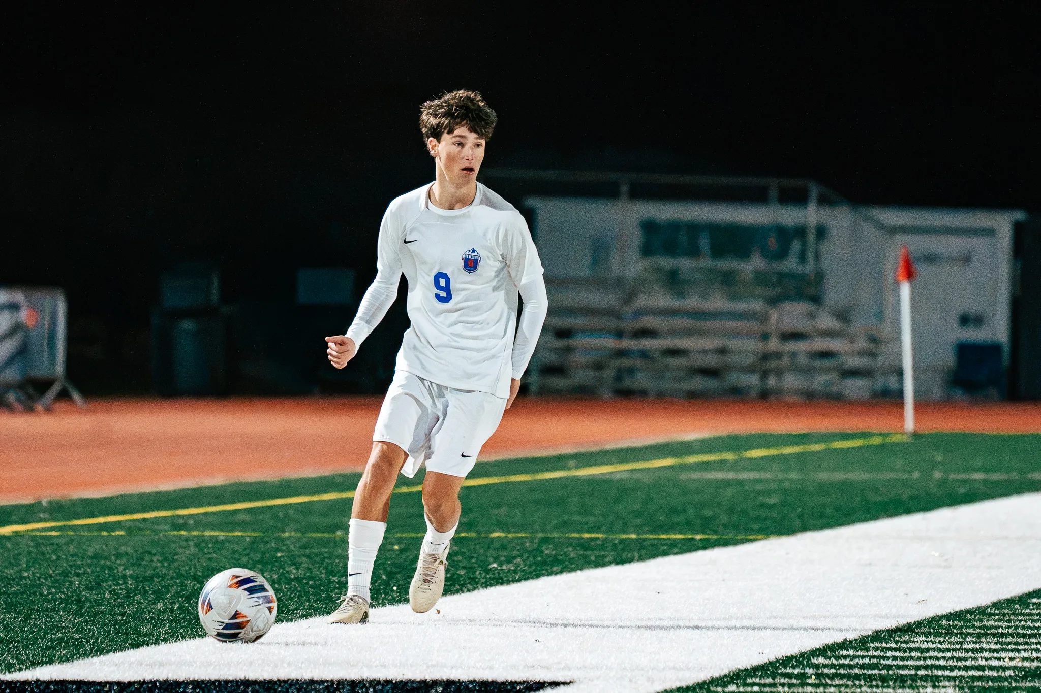 Centaurus number 9 brings the ball along the sideline near the corner flag, empty bleachers behind him