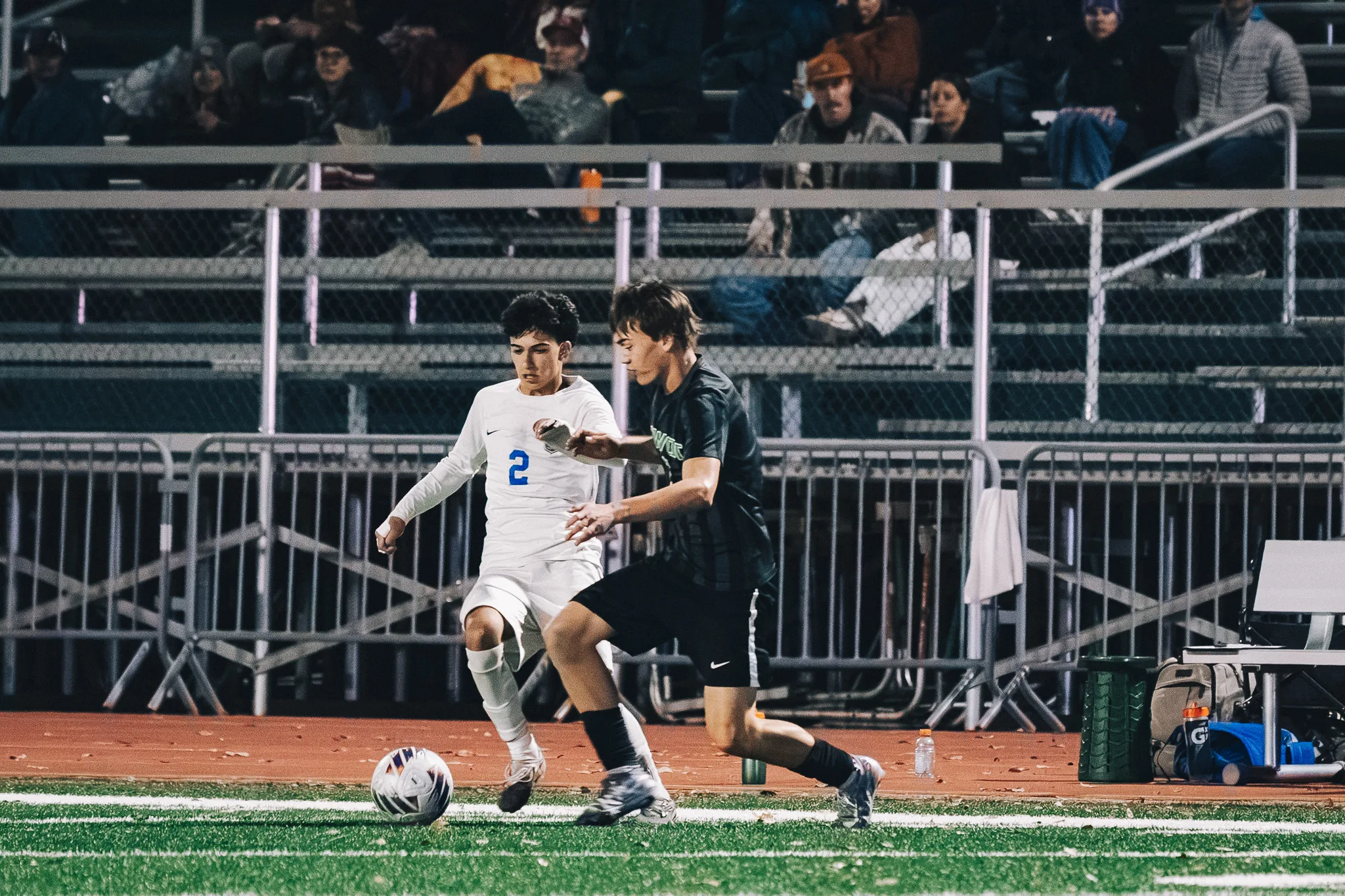 Centaurus number 2 and a Niwot player race shoulder to shoulder after the ball in front of the bleachers