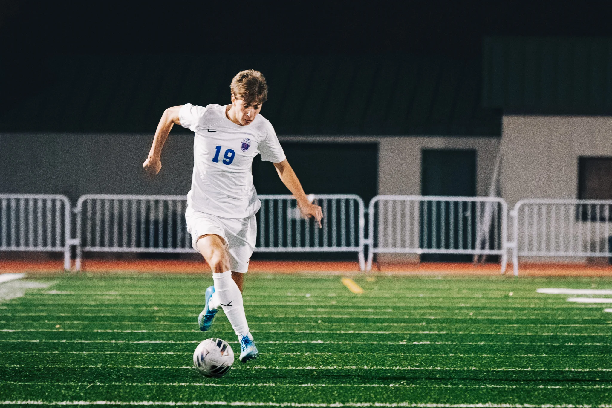 Centaurus number 19 in blue cleats dribbles forward with his eyes on the ball