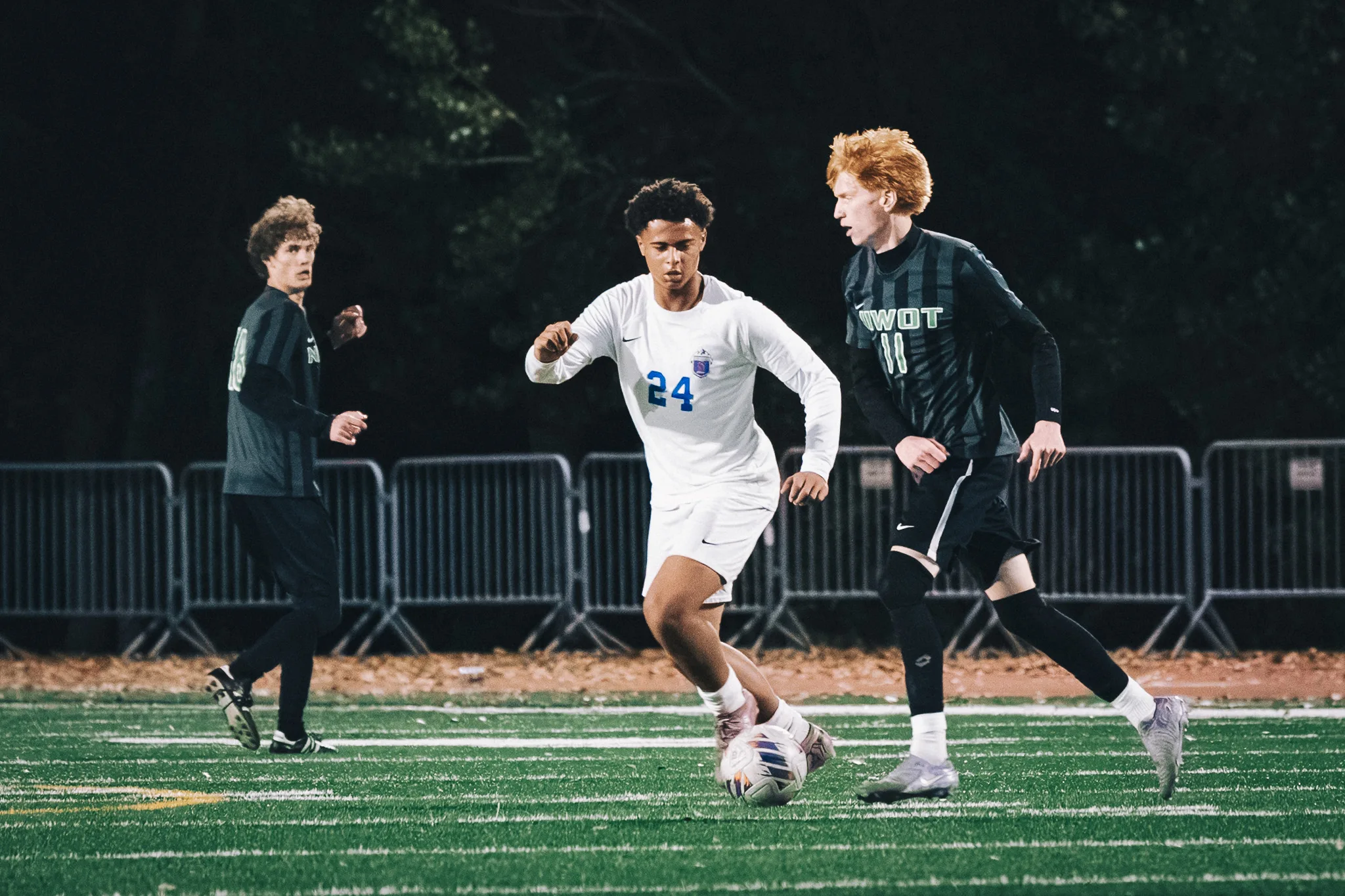 Centaurus number 24 carries the ball between two Niwot players, number 11 with red hair at the right