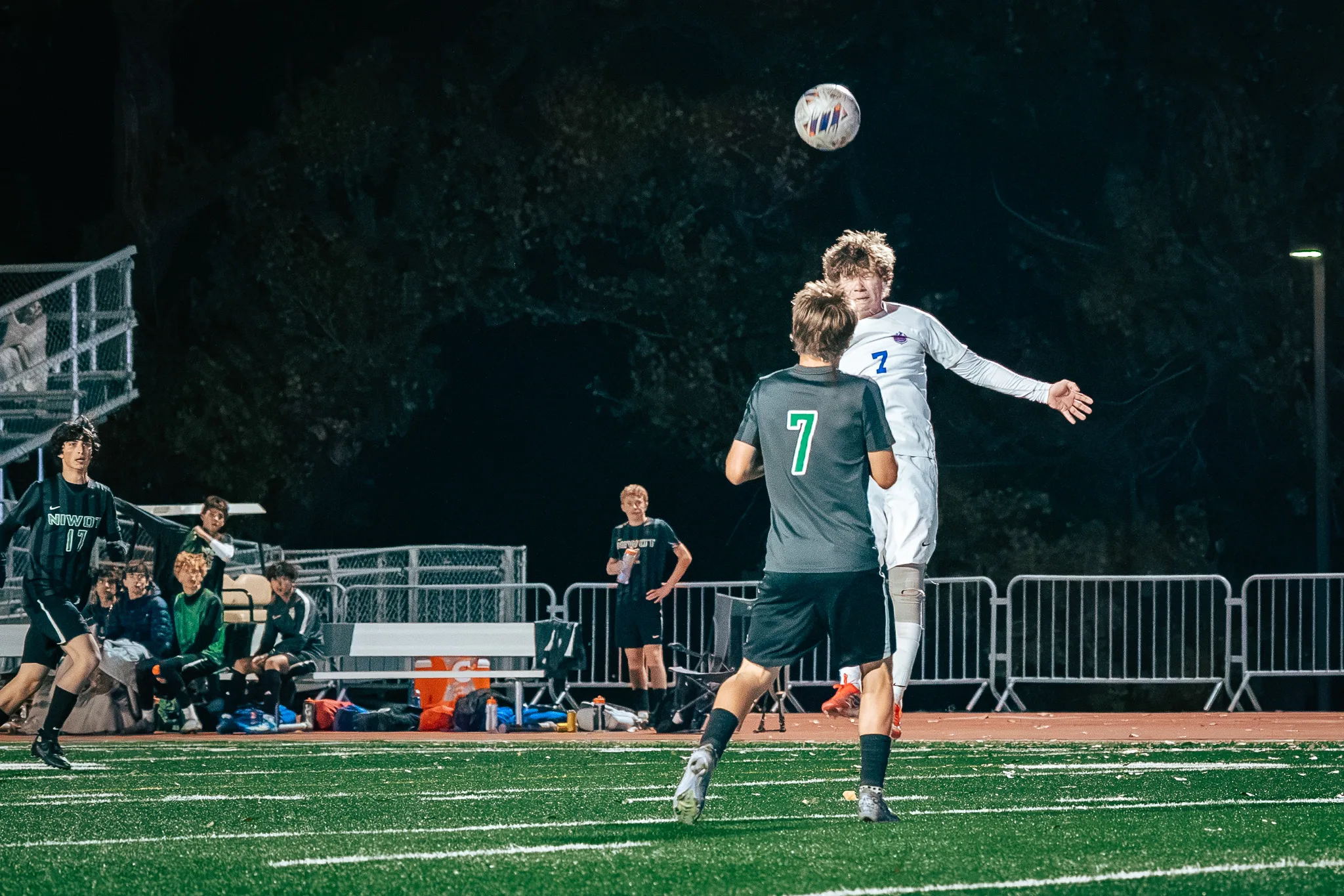 Centaurus number 7 rises to head the ball over Niwot number 7, the Niwot bench and Niwot number 17 at the left
