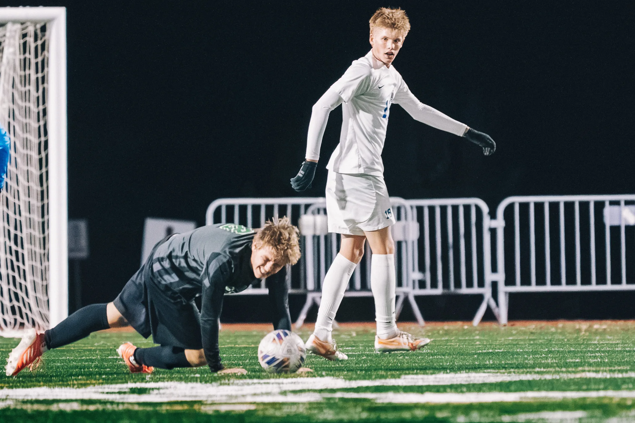 A Niwot player stumbles onto his hands beside the ball as a Centaurus player looks back over his shoulder, the goal at the left