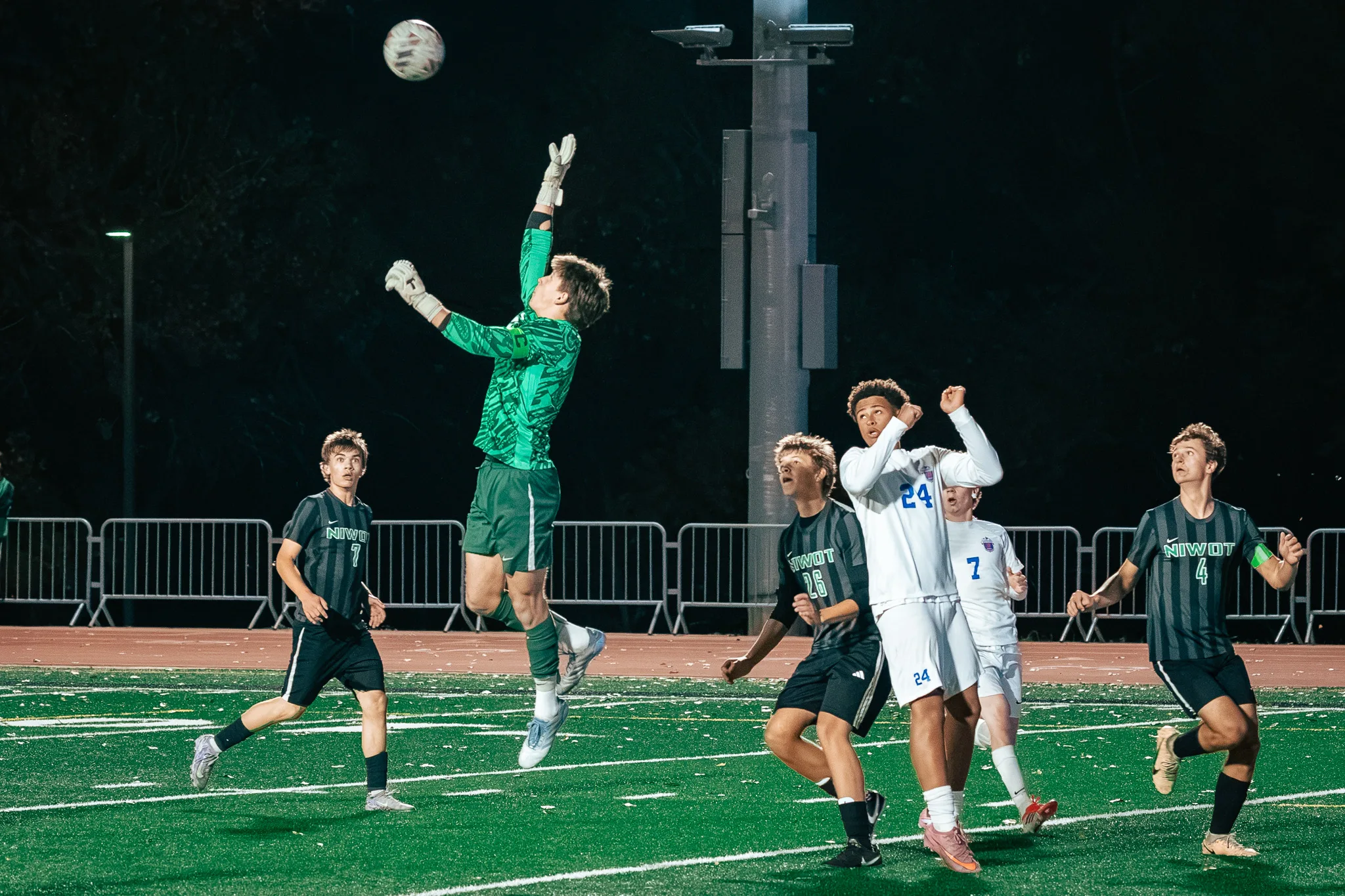 The Niwot goalkeeper in green leaps high for the ball as Centaurus numbers 24 and 7 and Niwot numbers 7, 26 and 4 watch from below