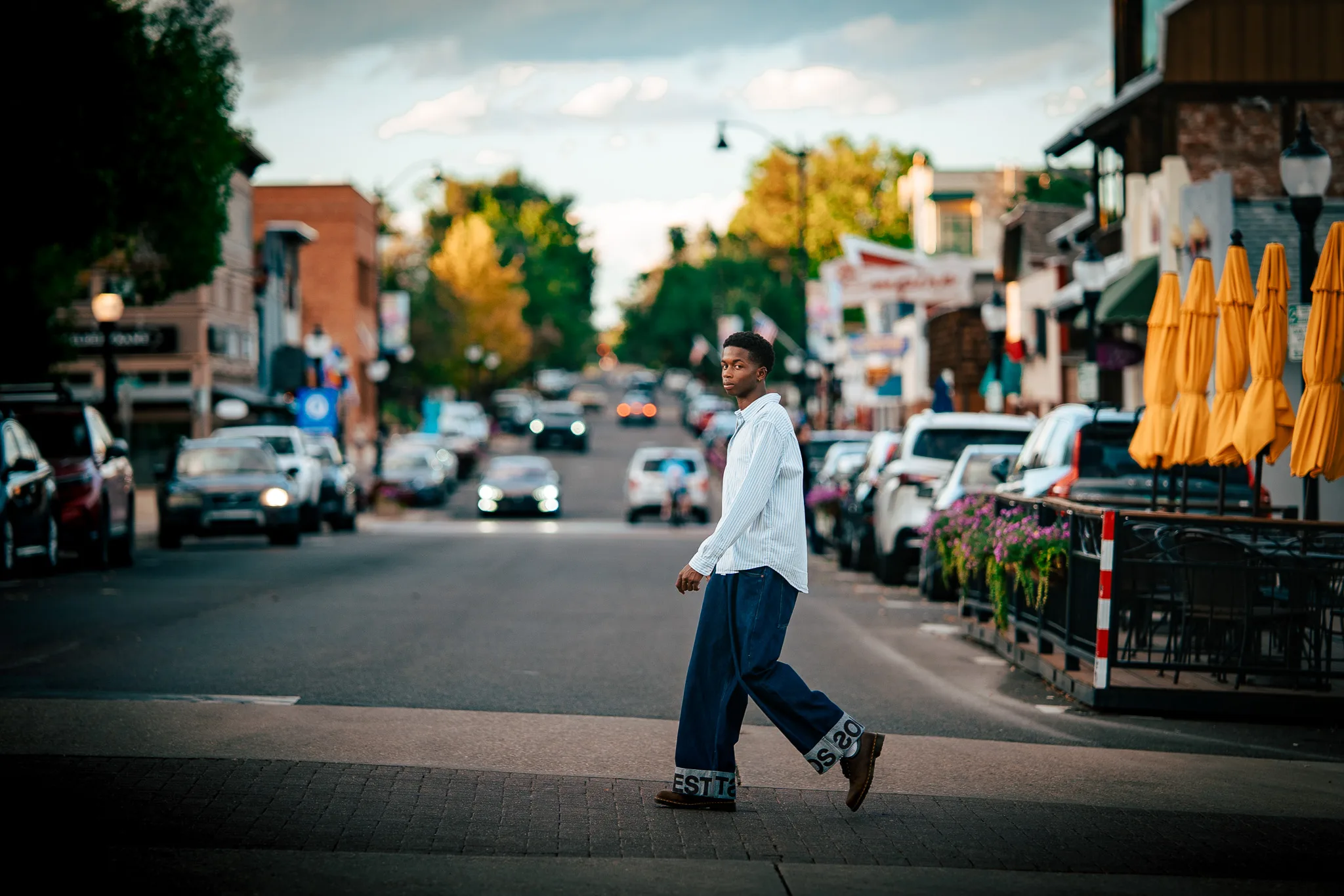 Charlie crosses Main Street in Louisville, lined with shops, parked cars and yellow patio umbrellas.