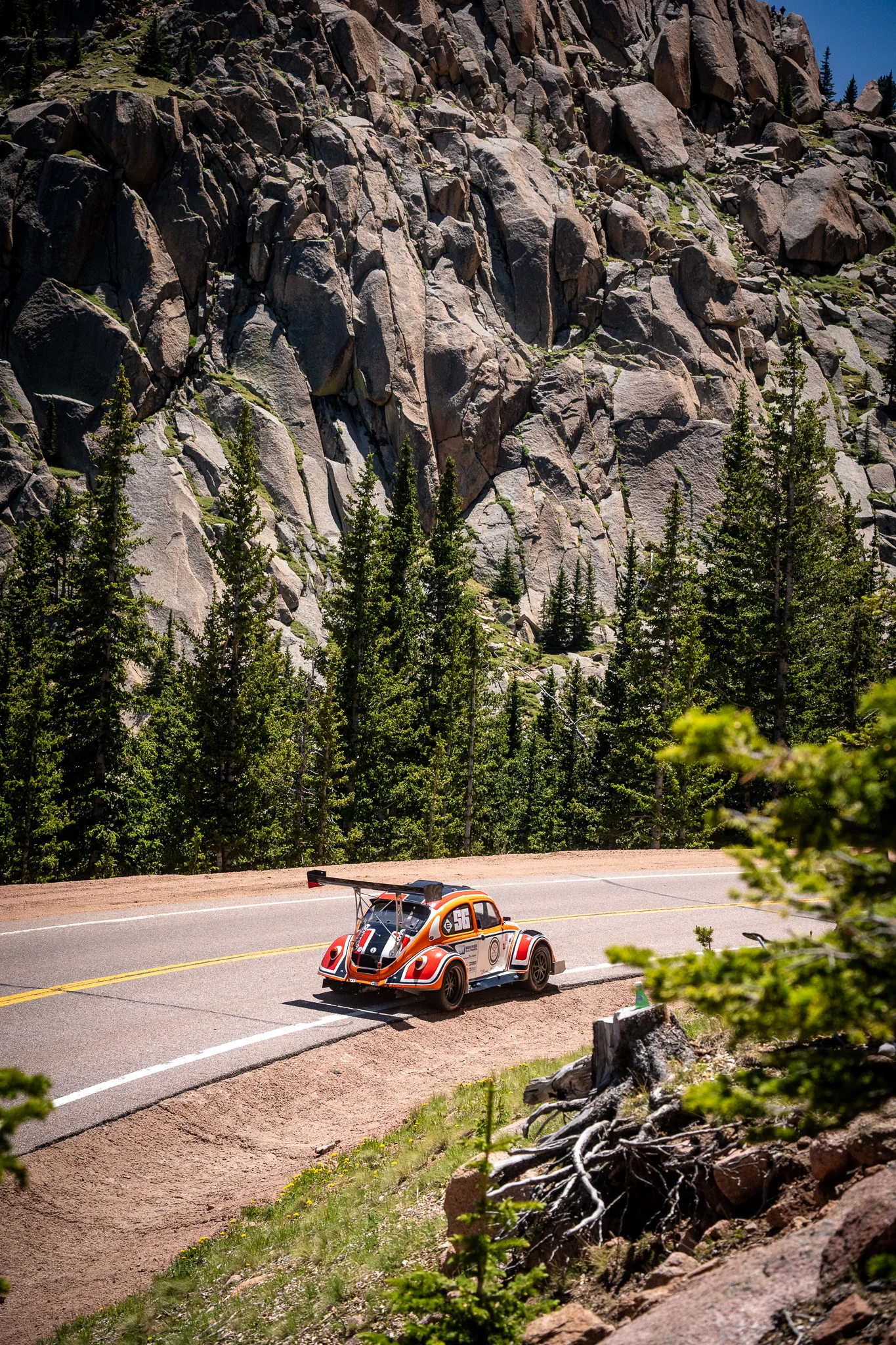 Grégoire Blachon's orange #56 electric Volkswagen Fun Cup EV on a switchback below the rock face at the 2025 Pikes Peak International Hill Climb