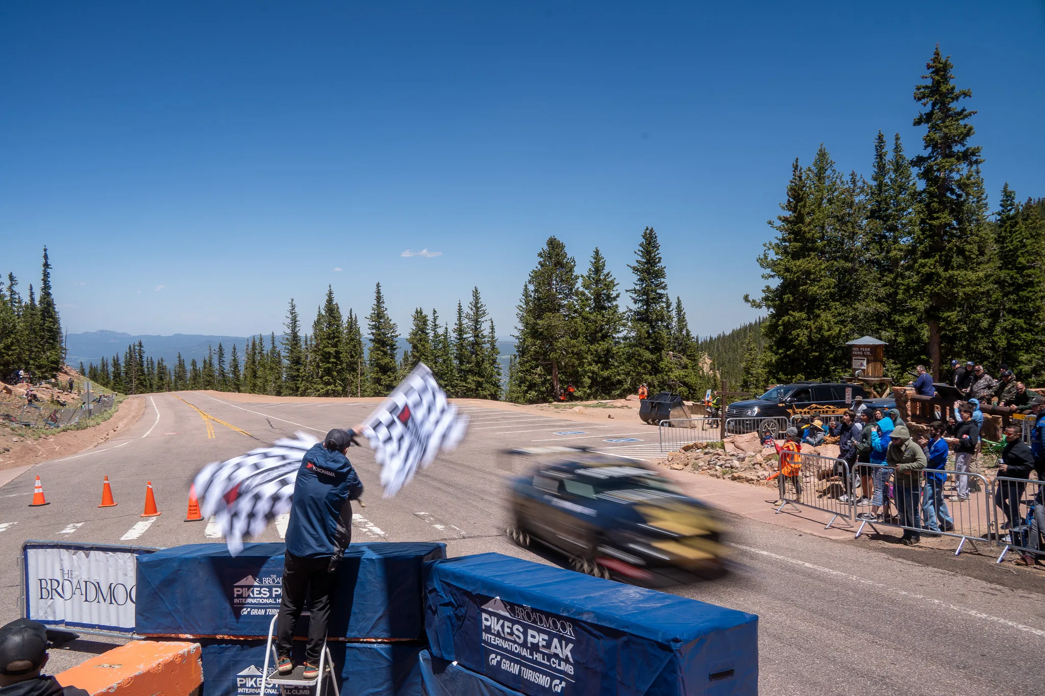 Checkered flag waving as a car blurs past the finish at the 2025 Pikes Peak International Hill Climb