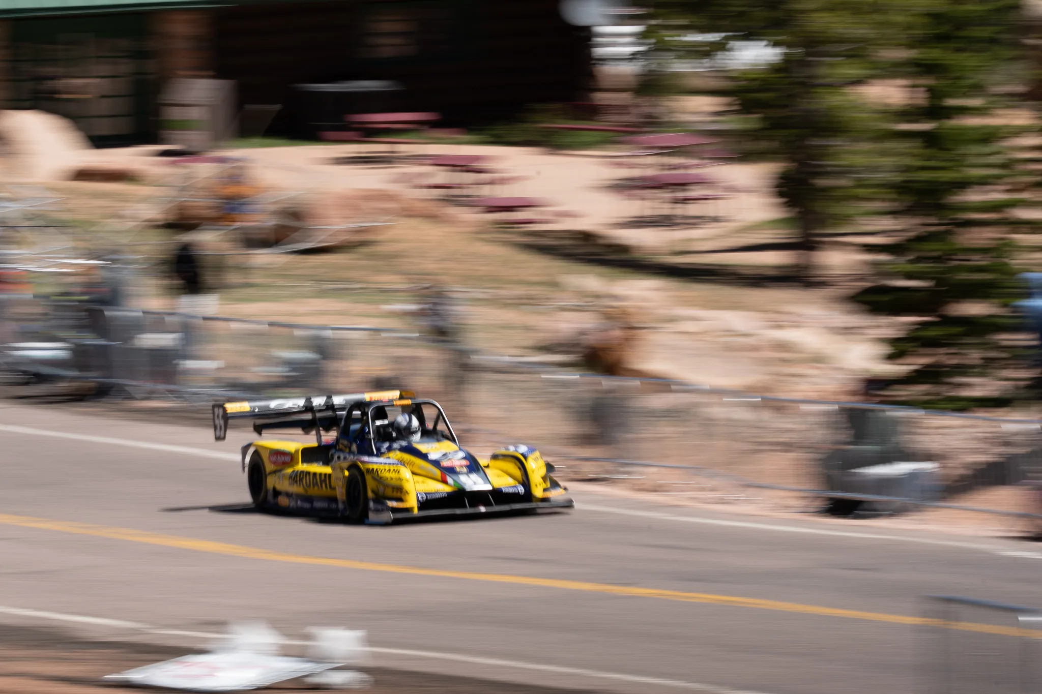 Panning shot of Simone Faggioli's yellow #55 Nova Proto NP01 Bardahl on the way to overall victory at the 2025 Pikes Peak International Hill Climb