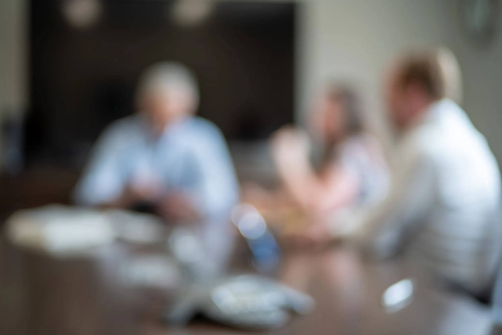 Out-of-focus view of three people in a meeting around a conference table with a speakerphone at Wick & Trautwein in Fort Collins.